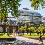 Frankfurt am Main, Germany - Aug. 20, 2023: People head towards the main entrance of the Palmengarten, one of three botanical gardens in Frankfurt, on a sunny summer afternoon.